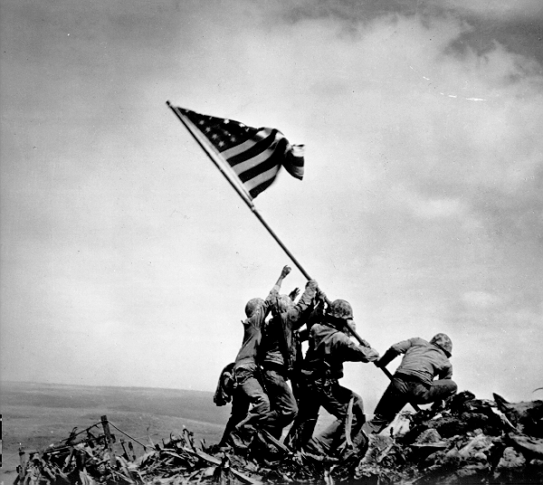 three Marines and one Navy seaman work to raise the USA flag on the top of mountain - Iwo Jima