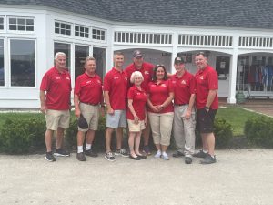 Group of 8 people with red shirts pose for group picture.