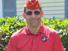 Marine Corps League man standing with sunglasses and red shirt