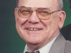 older man with glasses and a smile in a suite and tie