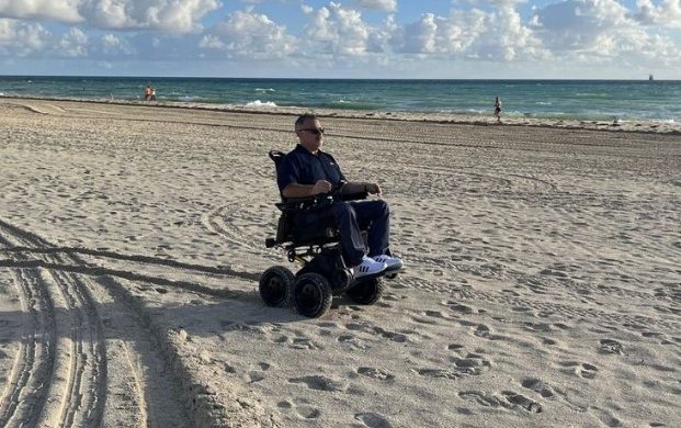 Man uses motorized iBot wheelchair on sand at the beach
